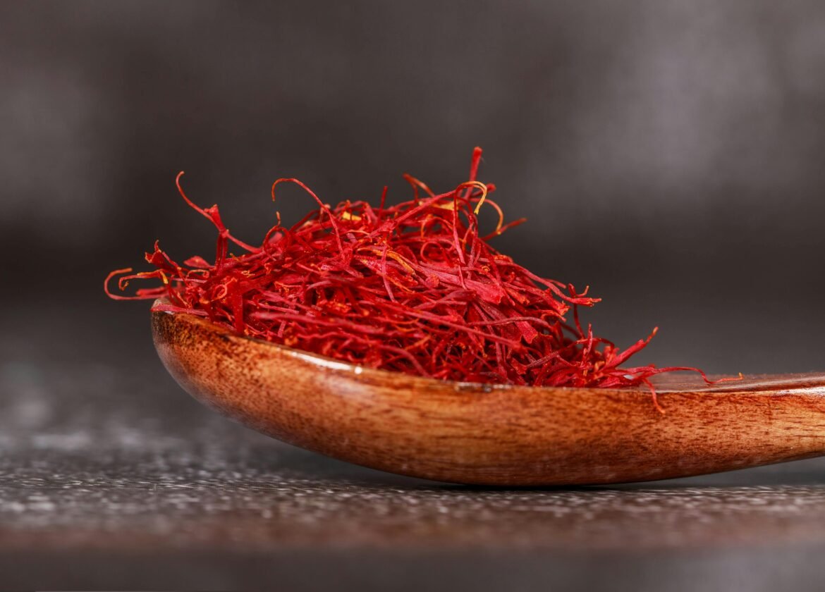 Detailed close-up of vibrant saffron threads in a wooden spoon, perfect for culinary imagery.