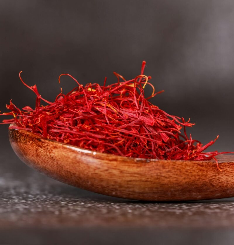 Detailed close-up of vibrant saffron threads in a wooden spoon, perfect for culinary imagery.