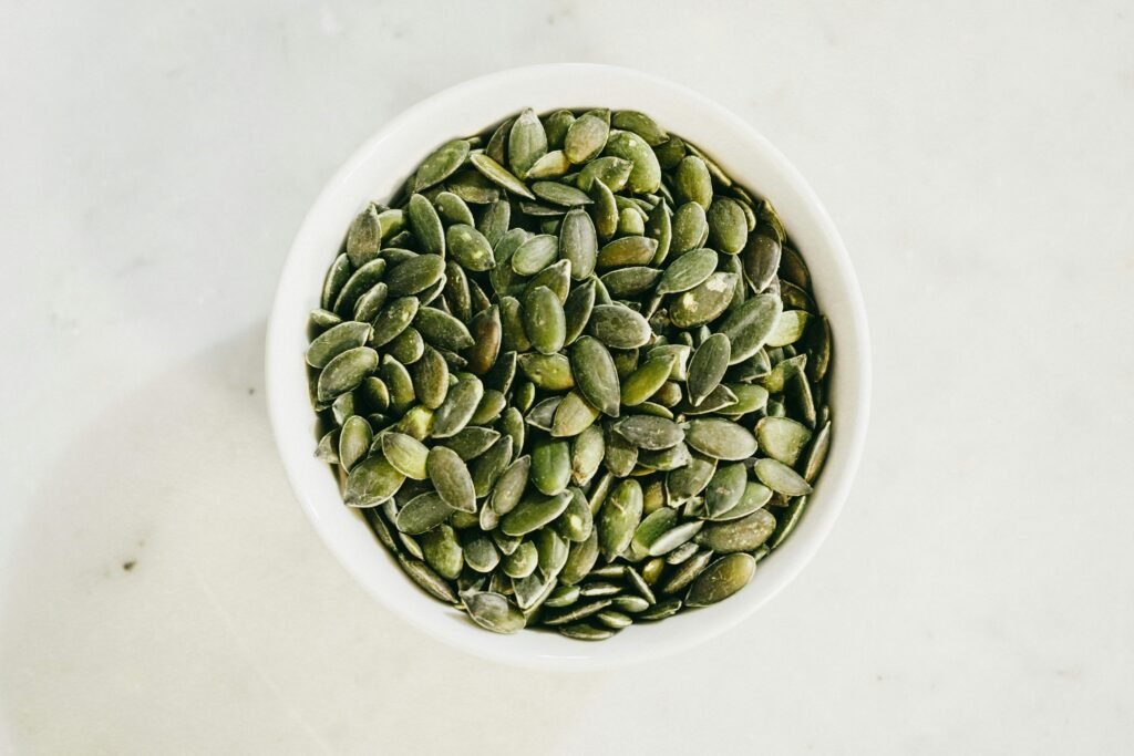 A bowl filled with fresh green pumpkin seeds, ideal for healthy eating.