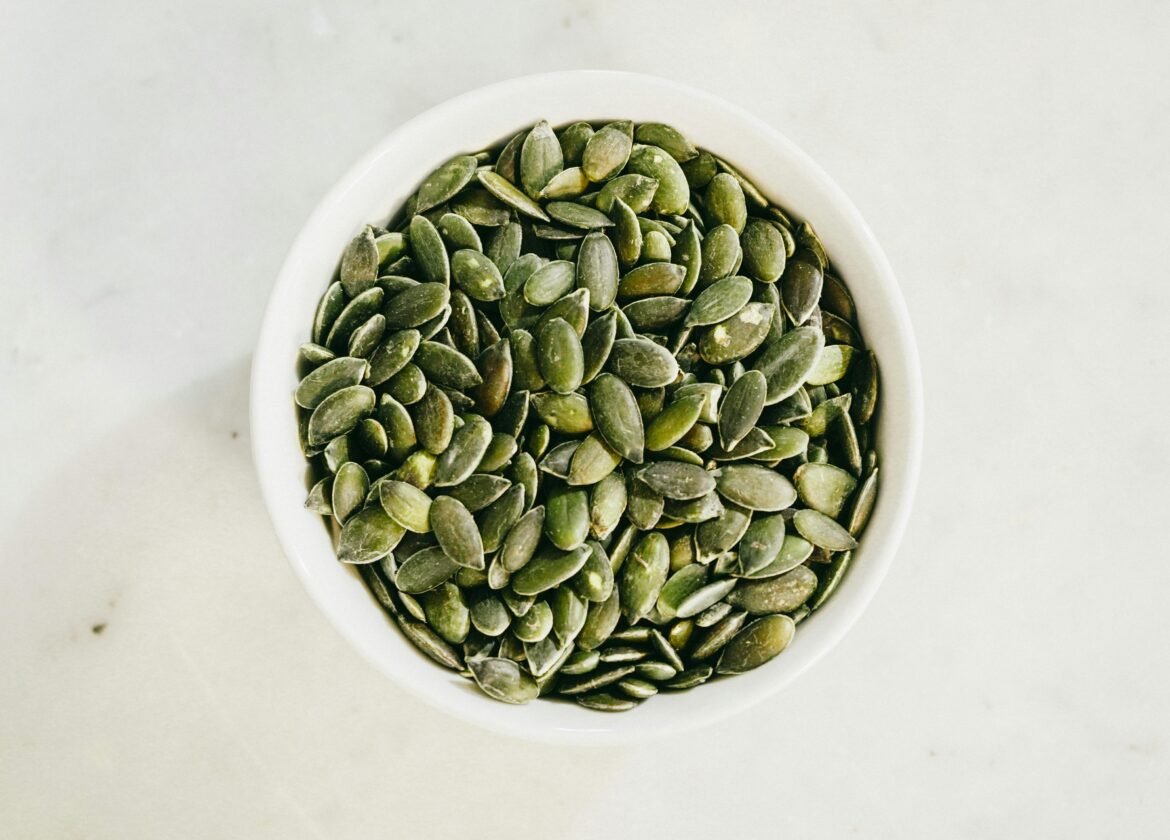 A bowl filled with fresh green pumpkin seeds, ideal for healthy eating.
