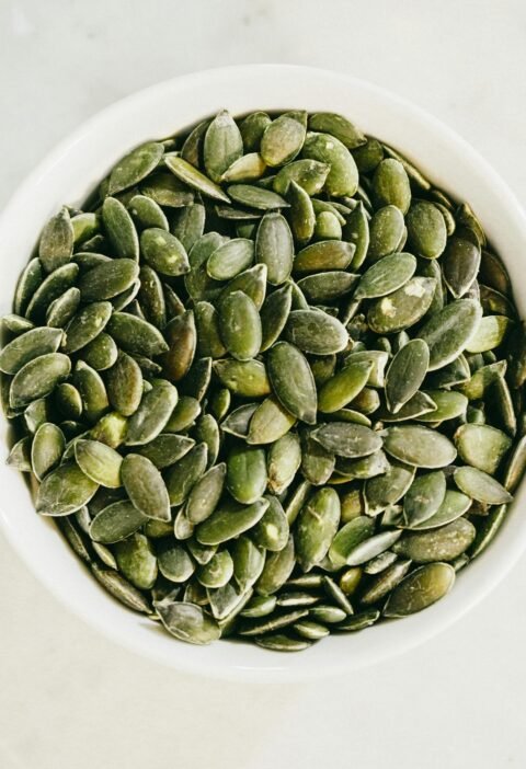 A bowl filled with fresh green pumpkin seeds, ideal for healthy eating.