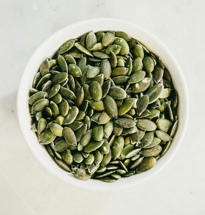 A bowl filled with fresh green pumpkin seeds, ideal for healthy eating.