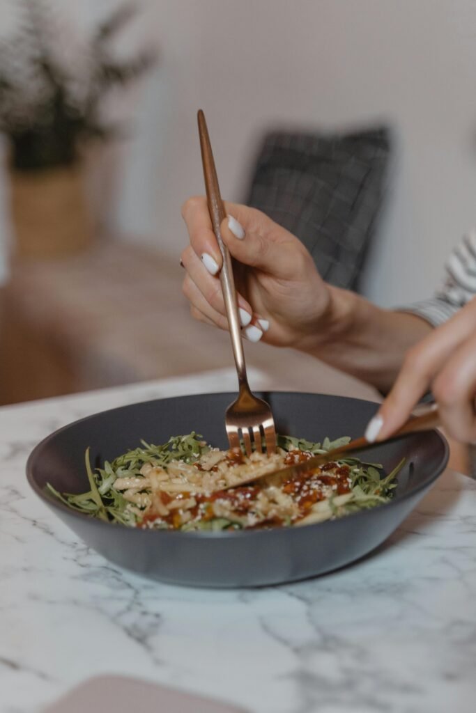Close-up of a person enjoying a fresh, healthy vegetarian meal with utensils.