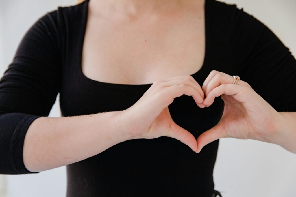 Close-up of a woman's hands making a heart gesture, symbolizing love.